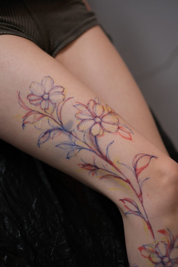 Freehand floral tattoo sketch drawn directly on leg